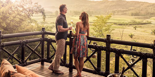 A romantic couple on a custom luxury safari, looking out over the savannah at sunset