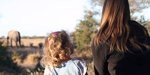 A girl and her mom on safari looking at elephants