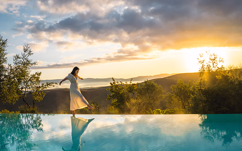 Lady walks along edge of infinity pool at a luxury villa