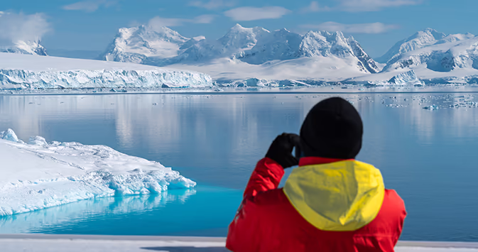 An adventure traveler looks at glaciers and icebergs on an adventurous expedition cruise to Antarctica