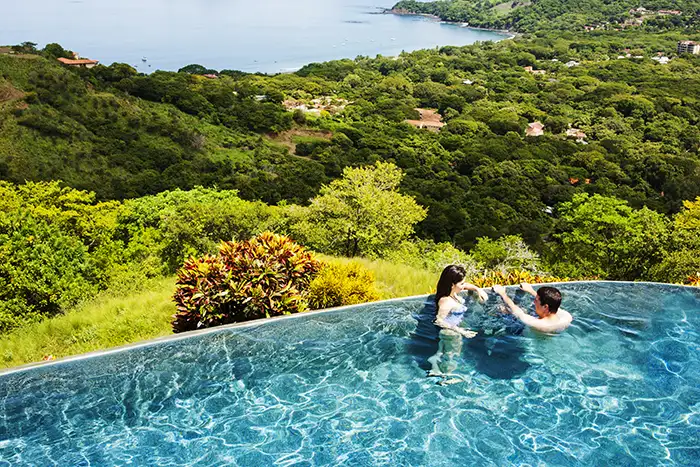 A couple in a pool overlooking Costa Rican jungle