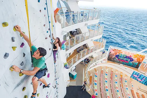 Two kids climb the rock wall on a Royal Caribbean ship
