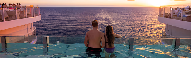 A couple stares at the sea from the infinity pool on a cruise ship